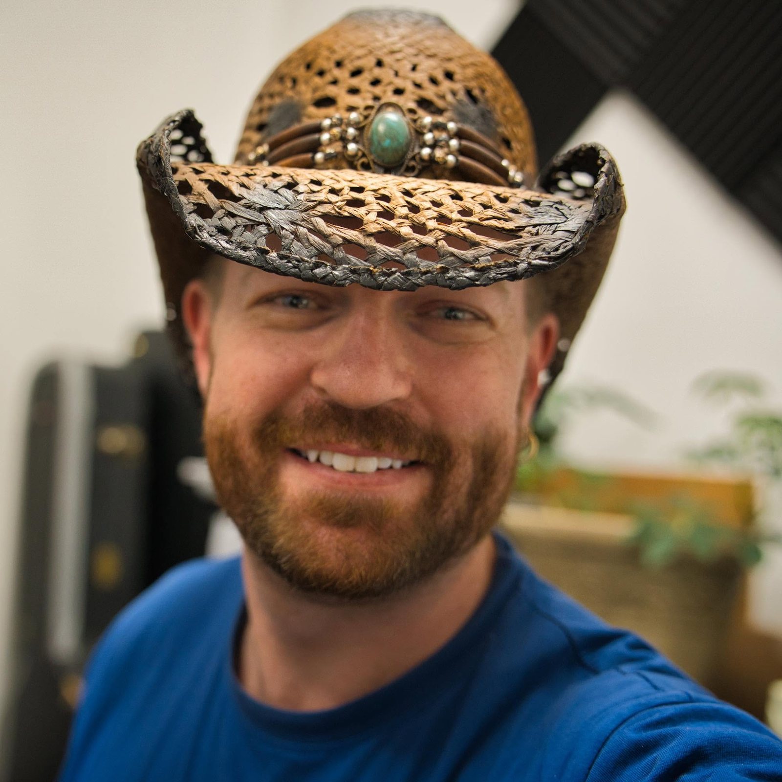 Micheal Lander, photographer, smiling in a weathered straw cowboy hat with a turquoise band
